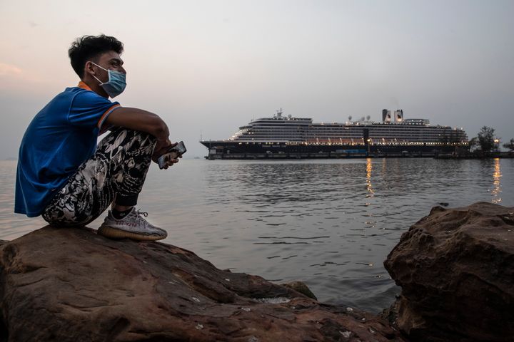 A Cambodian man sits by the ocean near the docked MS Westerdam cruise ship in Sihanoukville, Cambodia, on Monday. The cruise ship was carrying 1,455 passengers and 802 crew members before it docked.