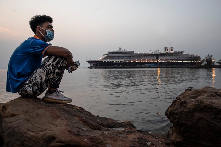 A Cambodian man sits by the ocean near the docked MS Westerdam cruise ship in Sihanoukville, Cambodia, on Monday. The cruise ship was carrying 1,455 passengers and 802 crew members before it docked.