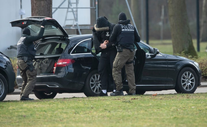 An unidentified person is brought to the Federal Supreme Court by police officers in Karlsruhe, Germany, Saturday, Feb 15, 2020. The person are one of among 12 men detained Friday in nationwide raids on suspicion of forming and supporting a “right-wing terrorist organization.” A federal judge on Saturday ordered the men held in investigative detention. (Uli Deck/dpa via AP)