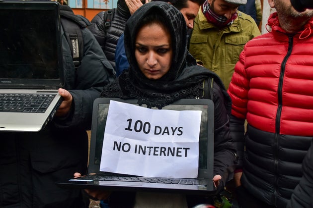 A Kashmiri journalist holds her laptop and a placard during the protest against the continuous ban on...
