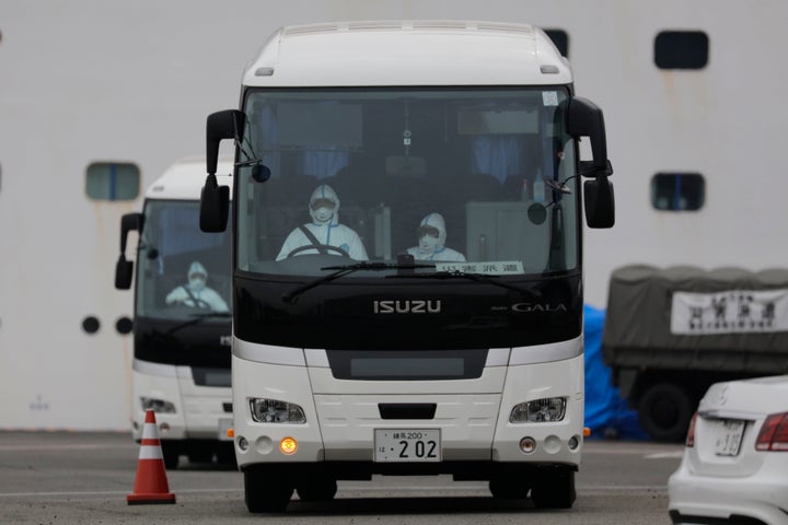 Two buses leave a port where the quarantined Diamond Princess cruise ship is docked in Yokohama on Saturday, Feb. 15.