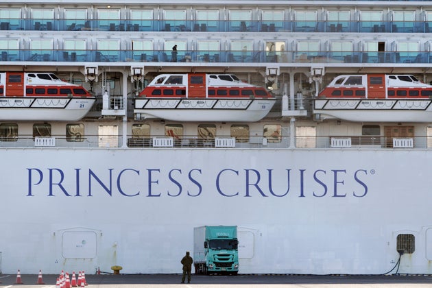 A passenger stands on the balcony of the quarantined cruise ship Diamond Princess on Sunday, Feb.