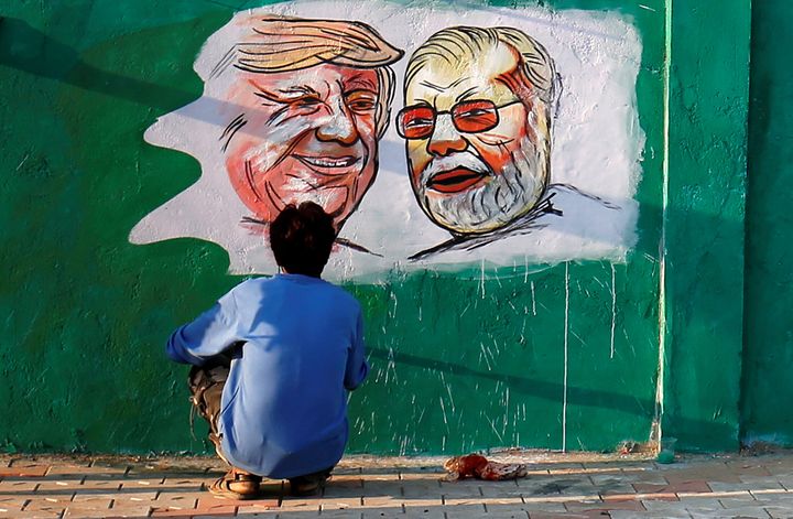 A man applies finishing touches to paintings of U.S. President Donald Trump and Indian Prime Minister Narendra Modi on a wall in Ahmedabad as part of a beautification drive along a route that the two politicians will be taking during Trump's upcoming visit.