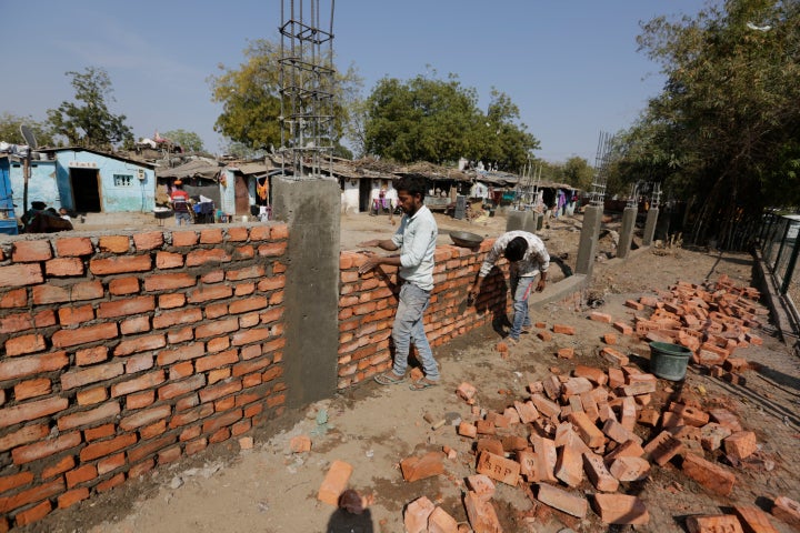 Workers construct a wall in front of a slum ahead of President Donald Trump's visit, in Ahmadabad, India.