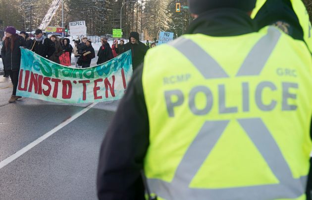 RCMP officers watch as supporters of the Wet'suwet'en Nation block a road outside of RCMP headquarters in Surrey, B.C., on Jan. 16, 2020. RCMP say they are aware of the request made by hereditary chiefs and discussions are underway.