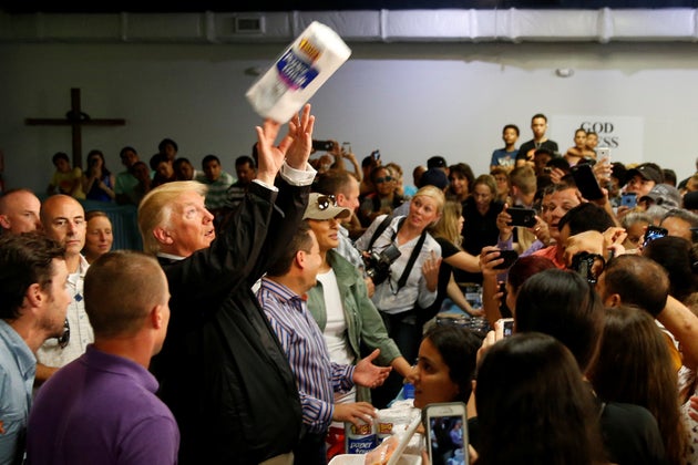 President Donald Trump tosses rolls of paper towels to people at a hurricane relief distribution center...