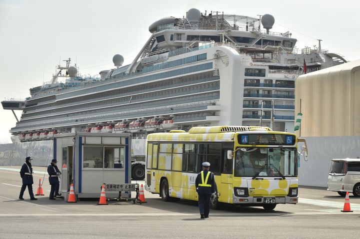 A bus carrying passengers who disembarked from the Diamond Princess cruise ship (back), in quarantine due to fears of the new COVID-19 coronavirus, leaves the Daikoku Pier Cruise Terminal in Yokohama on February 20, 2020. 