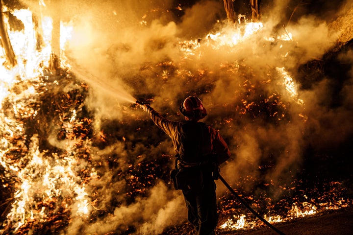 A firefighter sprays water while battling the spread of the Maria Fire as it moved quickly towards Santa Paula, California, on Nov. 1, 2019.