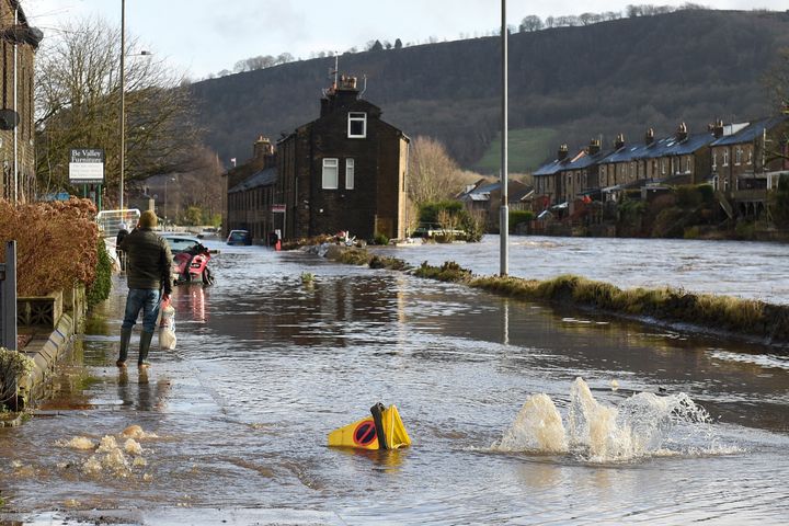 A man walks along a flooded street in Mytholmroyd, northern England, on February 9, 2020, after the River Calder burst its banks.
