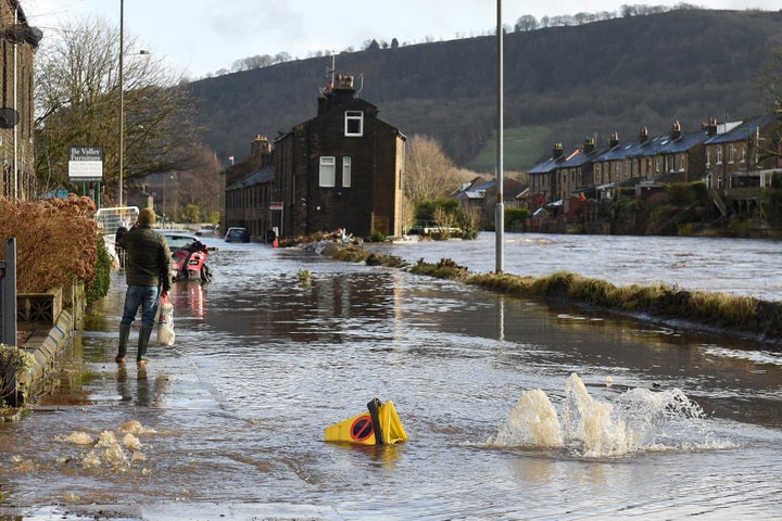 <strong>A man walks along a flooded street in Mytholmroyd, northern England, on February 9, 2020, after the River Calder burst its banks.</strong>