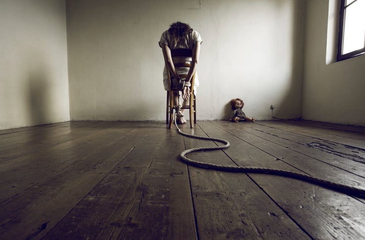 Young woman tied to a chair in a empty room