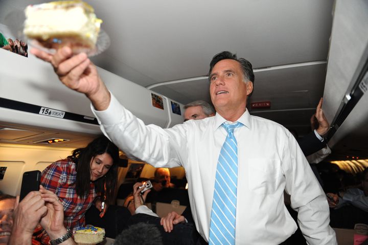 US Republican presidential candidate Mitt Romney hands NBC producer Scott Foster a piece of cake as he celebrates his birthday aboard the Romney campaign plane en route to Boston on September 14, 2012. AFP PHOTO/Nicholas KAMM (Photo credit should read NICHOLAS KAMM/AFP/GettyImages)