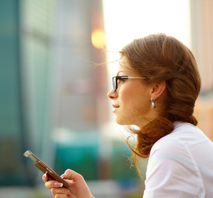 Pretty young business woman using mobile phone outdoor