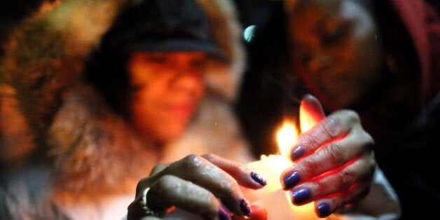 STATEN ISLAND, NY - DECEMBER 05: (L-R) Michele Sledge and Shannon Watkins light candles near Eric Garner's memorial for a can