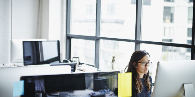 Businesswoman sitting at desk in high tech startup office working on computer