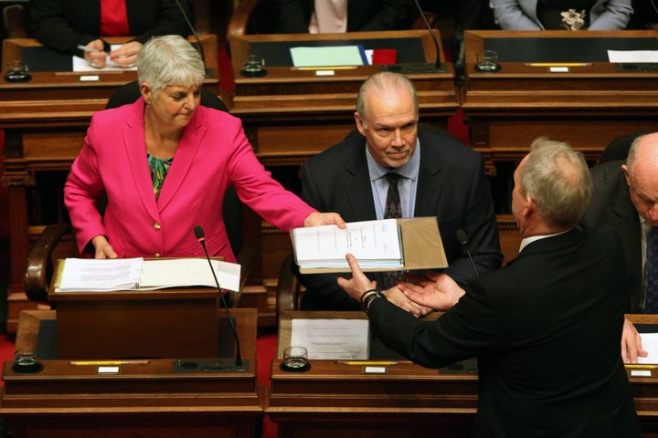 Premier John Horgan looks on as Minister of Finance Carole James passes on a copy of the budget.