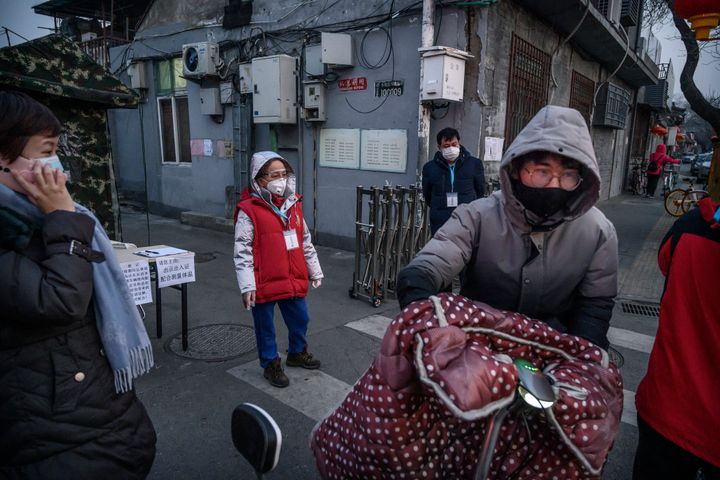 Members of a local neighbourhood committee wear protective masks as they turn away a visitor while standing guard at a barricade placed to control people entering and exiting a local hutong as part of government efforts to control the spread of the coronavirus on February 19, 2020 in Beijing, China. 