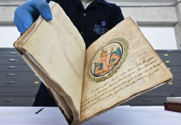 A conservation technician at the Peruvian National Library displays an invaluable manuscript with the...