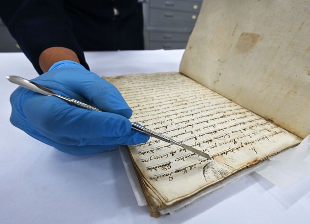 A conservation technician at the Peruvian National Library displays an invaluable manuscript with the...