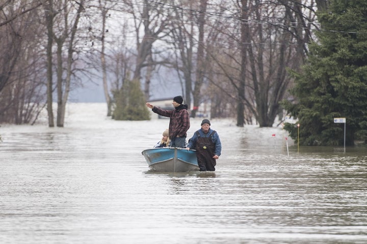 A man pulls people along a flooded residential street in a boat in west Montreal on April 26, 2019. Ottawa's bills for dealing with natural disasters neared half a billion dollars in two of the last three years.