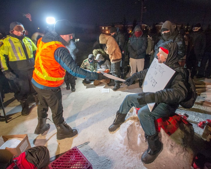 Police serve an injunction to protesters at a rail blockade in St-Lambert, south of Montreal, Que. on Thursday.
