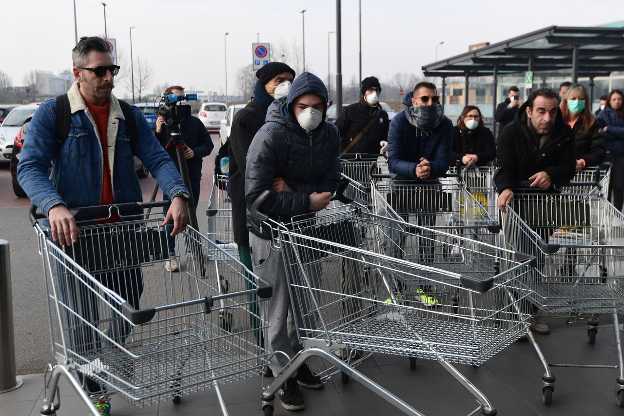 Residents wearing respiratory mask wait to be given access to shop in a supermarket in small groups of forty people in the small Italian town of Casalpusterlengo.