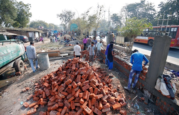 Construction workers build a wall along a slum area as part of a beautification drive along a route that U.S. President Donald Trump and Prime Minister Narendra Modi will be taking during Trump's visit.