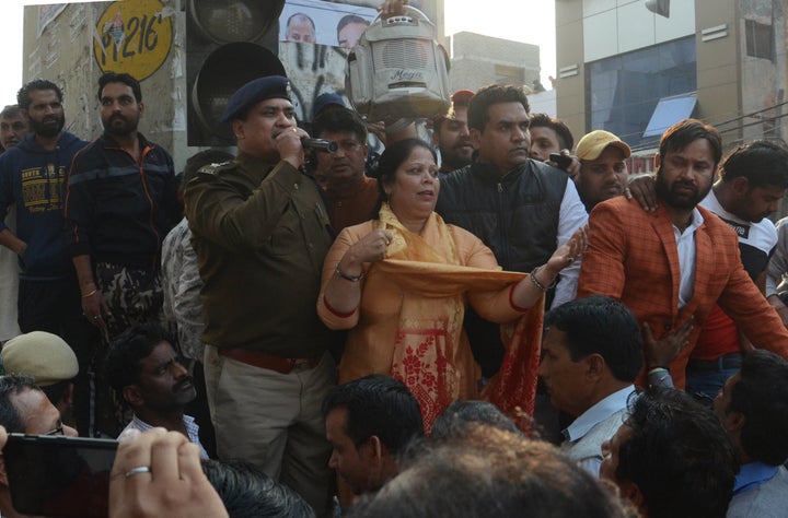 A police personnel addresses the crowd in the presence of BJP leader Kapil Mishra, at Maujpur, on Sunday in New Delhi.