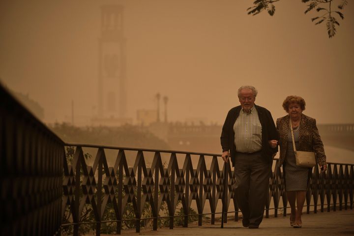 A couple walk across a bridge in a cloud of red dust in Santa Cruz de Tenerife.