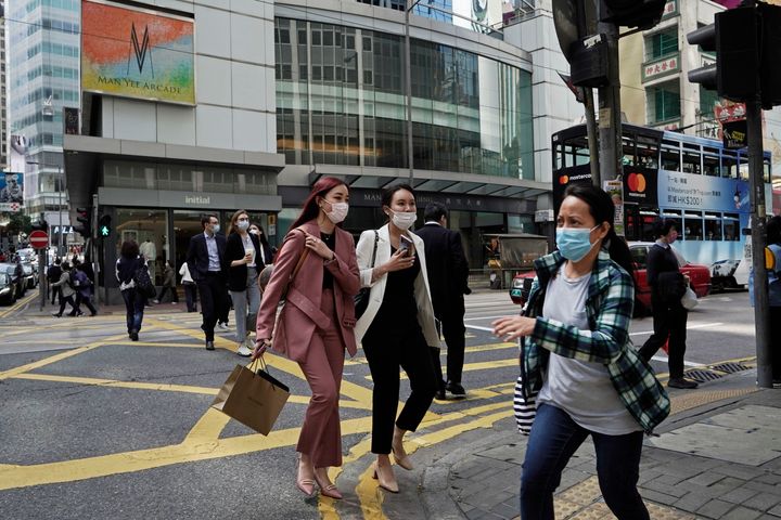 People wearing masks walk across a street in Hong Kong on Monday. COVID-19 has sickened thousands of people throughout China and other countries since December.