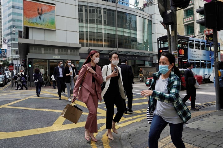 People wearing masks walk across a street in Hong Kong on Monday. COVID-19 has sickened thousands of people throughout China