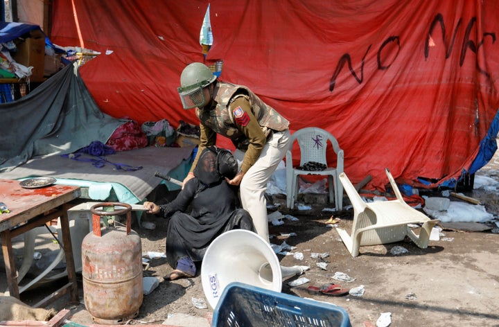 A woman opposing the new citizenship law is helped by a policeman after she was beaten by people supporting the law, at a protest site in New Delhi, February 24, 2020.