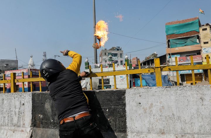 A man throws a petrol bomb at a Muslim shrine during the riots in Delhi on Monday. 