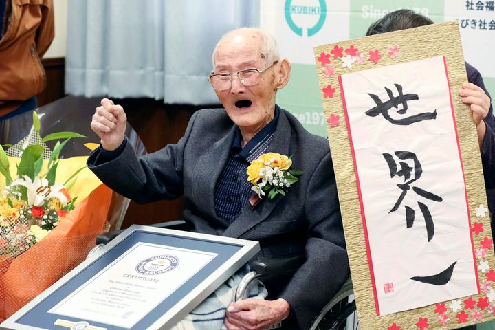 In this Feb. 12, 2020 file photo, Chitetsu Watanabe, 112, poses next to the calligraphy he wrote after being awarded as the world's oldest living male by Guinness World Records.