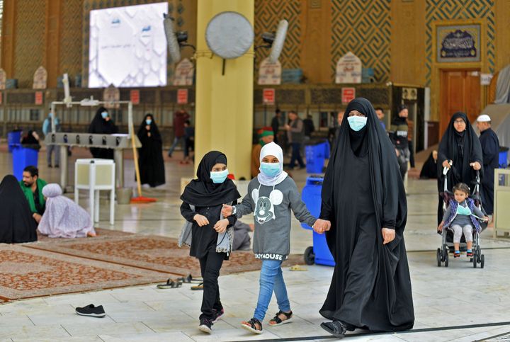 Pilgrims wearing masks walk through the courtyard of the shrine of Imam Ali on February 25, 2020 in the holy Iraqi central city of Najaf, where the first case of coronavirus COVID-19 has been documented in Iraq.
