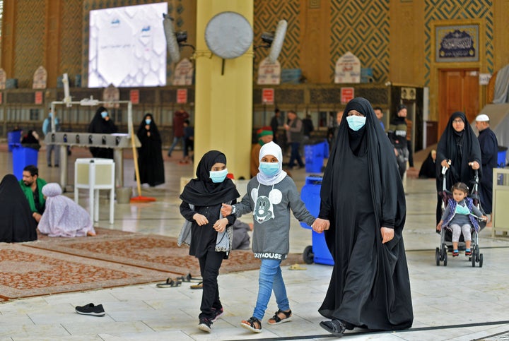 Pilgrims wearing masks walk through the courtyard of the shrine of Imam Ali on February 25, 2020 in the holy Iraqi central city of Najaf, where the first case of coronavirus COVID-19 has been documented in Iraq.