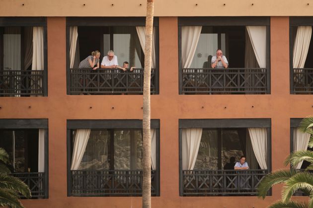 People stand on their balconies of the H10 Costa Adeje Palace hotel in the Canary Island of Tenerife, Spain, Tuesday, Feb. 25, 2020. Spanish officials say a tourist hotel on the Canary Island of Tenerife has been placed in quarantine after an Italian doctor staying there tested positive for the COVID-19 virus and Spanish news media says some 1,000 tourists staying at the complex are not allowed to leave. (AP Photo)