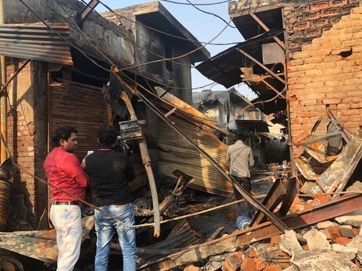 People walk through the destruction left after a fire was started by rioters in Delhi's Gopalpuri. 