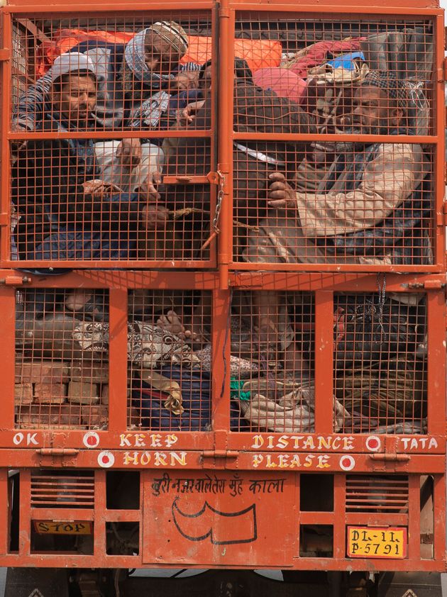 A group of Muslims huddle together in the back of a mini truck and leave the area after Tuesday's violence in New Delhi.