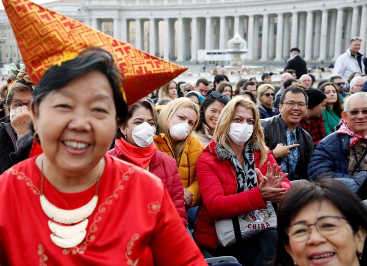 People, a few in face masks, wait for Pope Francis to arrive for his weekly general audience at the Vatican.