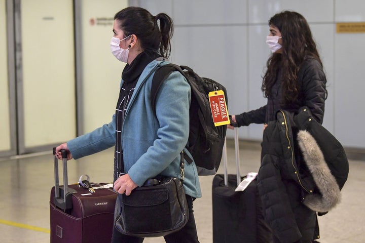 Passengers wear masks as a precautionary measure against the new coronavirus as they travel Wednesday through Guarulhos International Airport in Sao Paulo, Brazil.