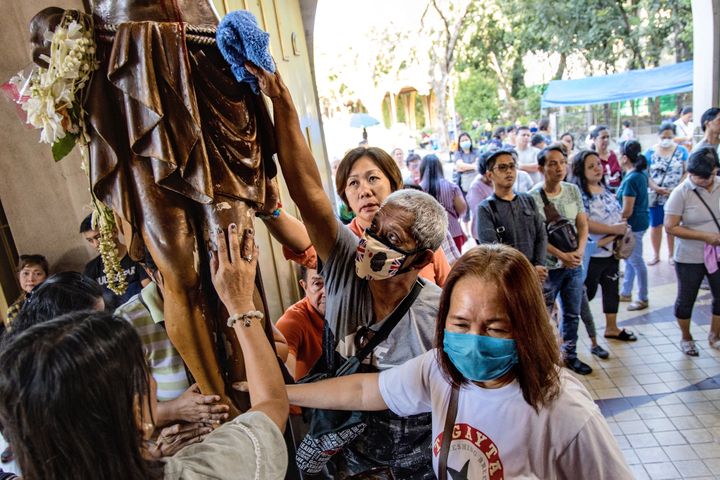 Filipino Catholics wearing protective masks touch an image of Jesus Christ during Ash Wednesday services at a church in Paranaque city, Metro Manila, Philippines.