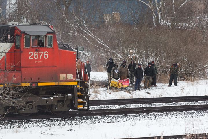 Protesters stand next to the tracks as a CN train moves through Tyendinaga Mohawk Territory, near Belleville, Ont., on Feb. 26, 2020.