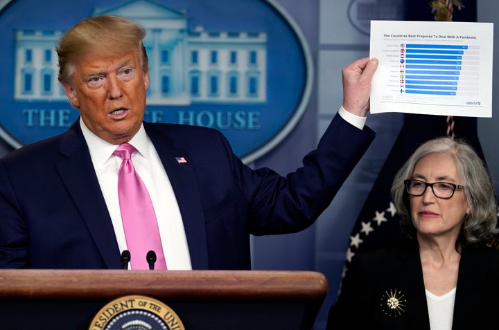 President Donald Trump, with members of the president's coronavirus task force, holds a paper about countries best prepared t