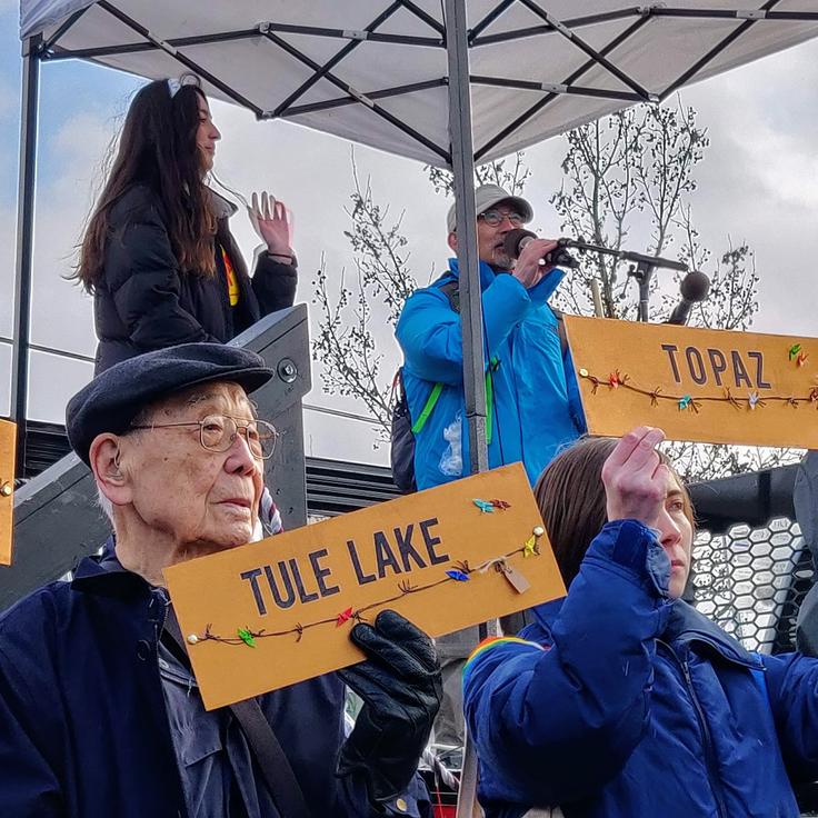 Homer Yasui holds a placard with the name of the camp where he was incarcerated during World War II, part of a protest Sunday in Tacoma, Washington, at a present-day immigrant detention center.