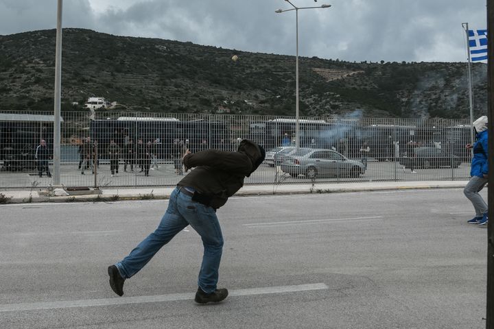 Διαδηλωτής επί το έργον με στόχο τις κλούβες των ΜΑΤ στο λιμάνι της Χίου.