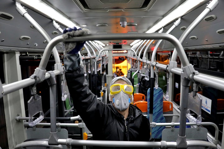 A worker disinfects a public bus against coronavirus in Tehran, Iran, on the early morning of Wednesday, Feb. 26, 2020. (AP P