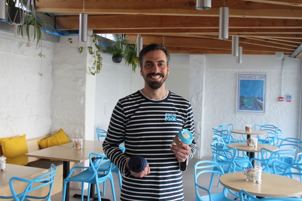 Sam Dean at the Jubilee Café in Penzance with some of the reusable glass coffee cups he sells.