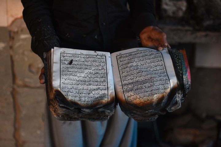 A man holds the holy Quran that was burnt along with the mosque at Mustafabad, on February 26, 2020 in New Delhi, India. 