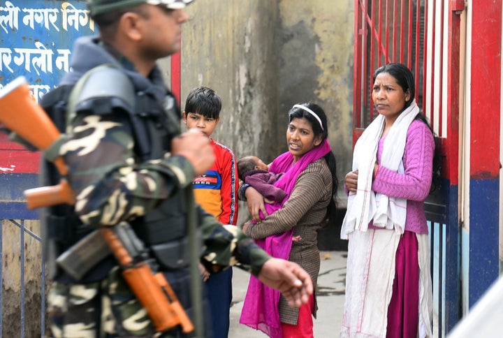 Residents look on as police and paramilitary personnel conduct a patrol in the area between Maujpur and Jaffrabad, on February 26, 2020 in New Delhi.